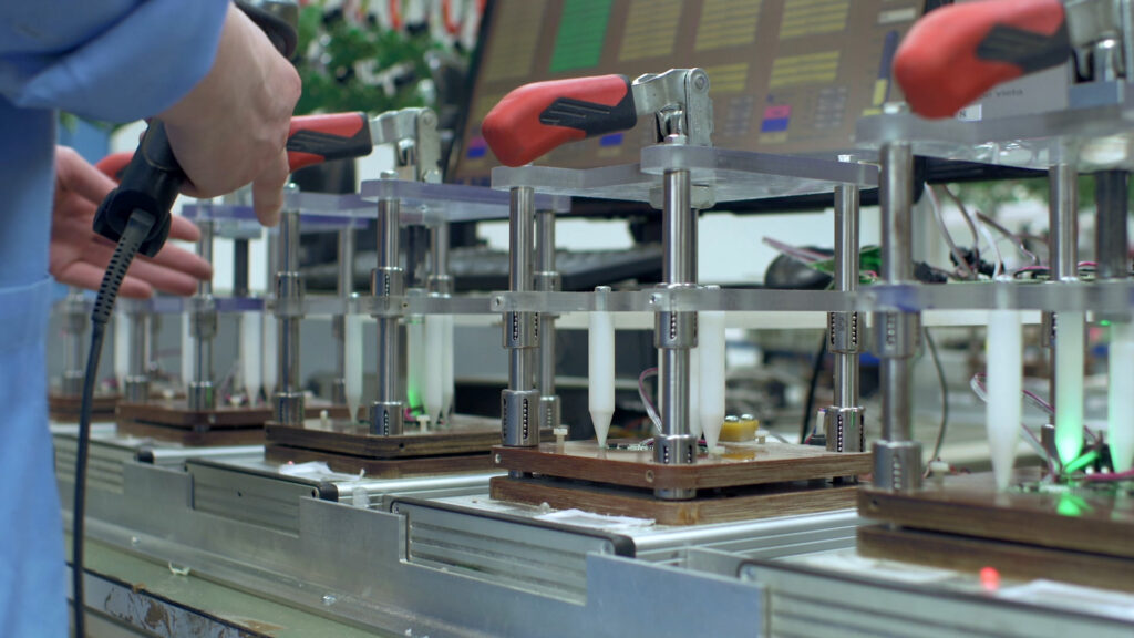 stock photo of a lab type of setting, an operator manipulates a red handle that seems to control plastic syringes