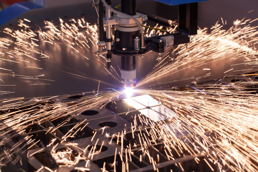 Industrial CNC/laser cutting machine cutting through metal and resulting sparks flying