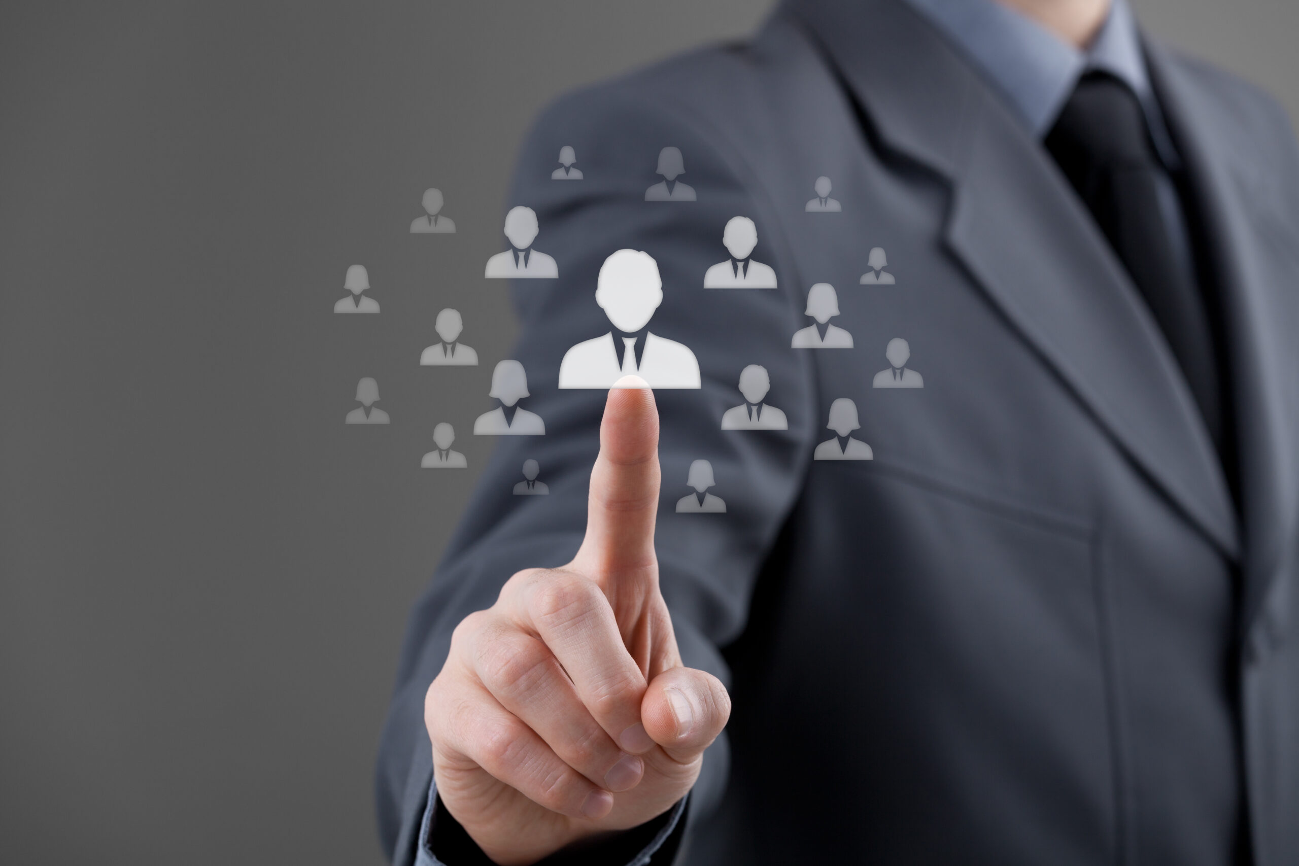 Man in suit pointing at and selecting from a variety of white avatar icons of a professional in a tie